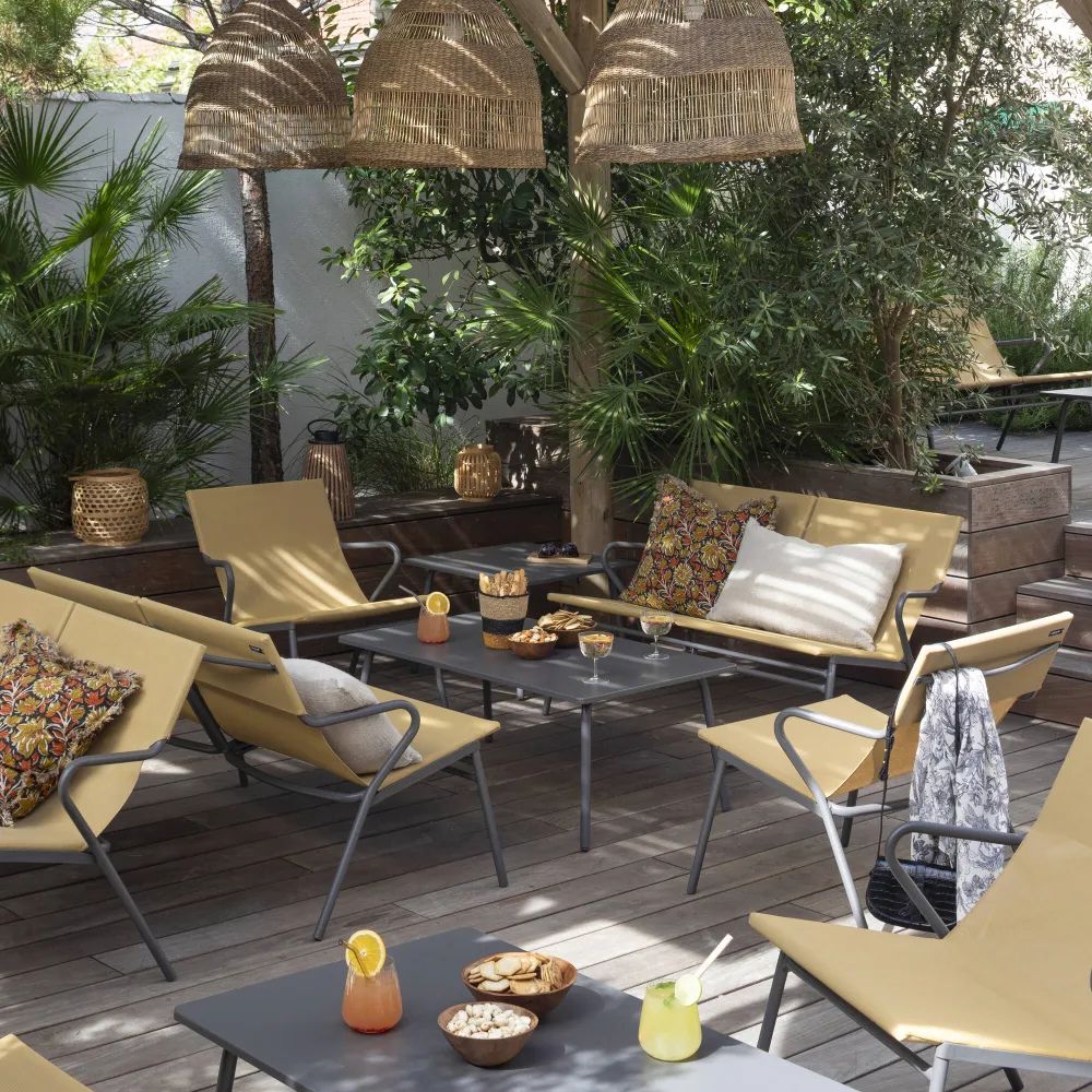 Espace lounge extérieur équipé de mobilier professionnel LAFUMA avec banquettes basses en toile Batyline Jaune Safran, idéal pour CHR.