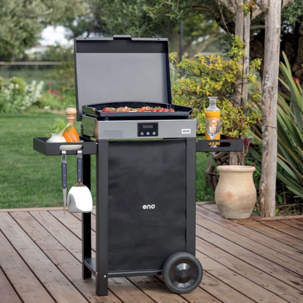 Plancha électrique INITIAL 50 sur chariot ENO en extérieur, avec couvercle ouvert et aliments en cuisson.