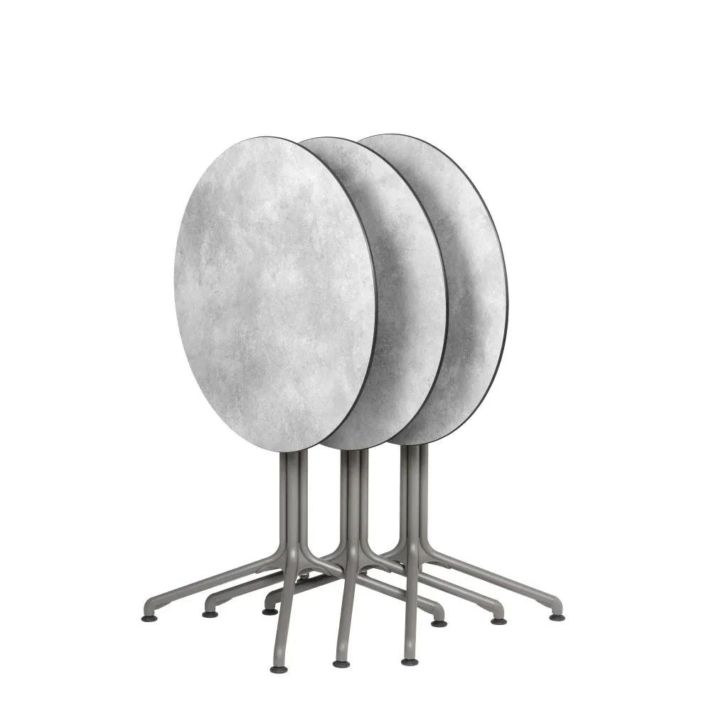 Pieds de table centraux LAFUMA HORIZON rabattables, empilés avec plateaux ronds.