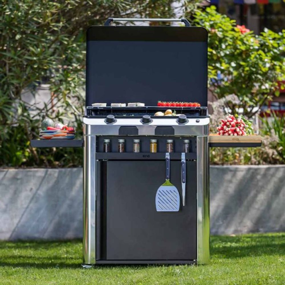 Plancha Fusion 75 sur chariot en extérieur, équipée d’un rangement porte-épices et d’ustensiles de cuisine.