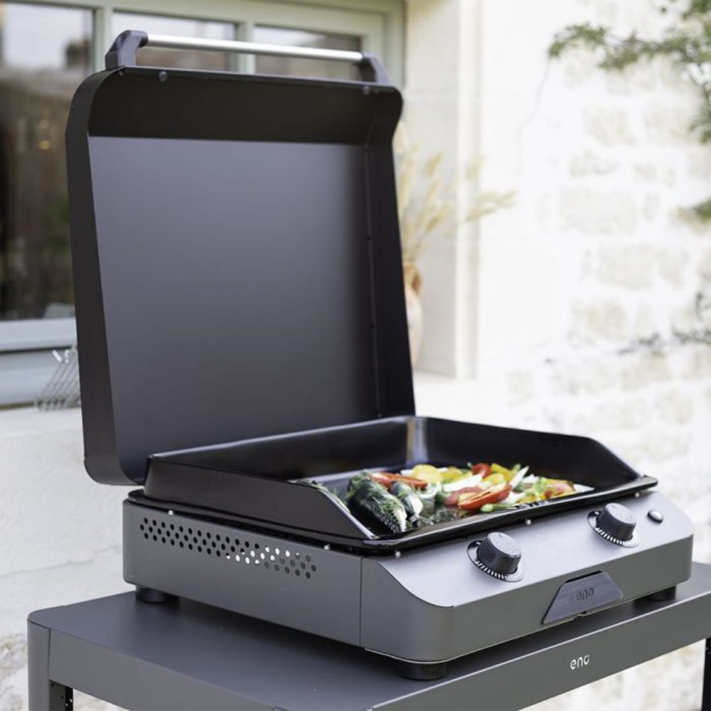 Plancha Fusion 60 en extérieur avec couvercle ouvert, cuisson de légumes.