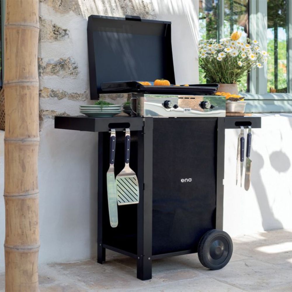 Plancha Initial installée en extérieur avec accessoires accrochés au chariot et couvercle ouvert.
