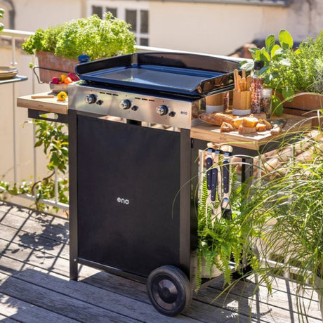 Plancha gaz Initial 65 en utilisation sur une terrasse avec accessoires et aliments prêts à cuire.