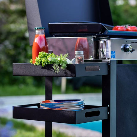 Tablette amovible fixée sur un chariot de plancha, utilisée comme espace de rangement et de service.