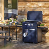 Barbecue gaz Enosign bleu navy sur chariot en acier, installé sur une terrasse en bois avec des herbes aromatiques et accessoires de cuisine. Idéal pour la cuisson en extérieur.